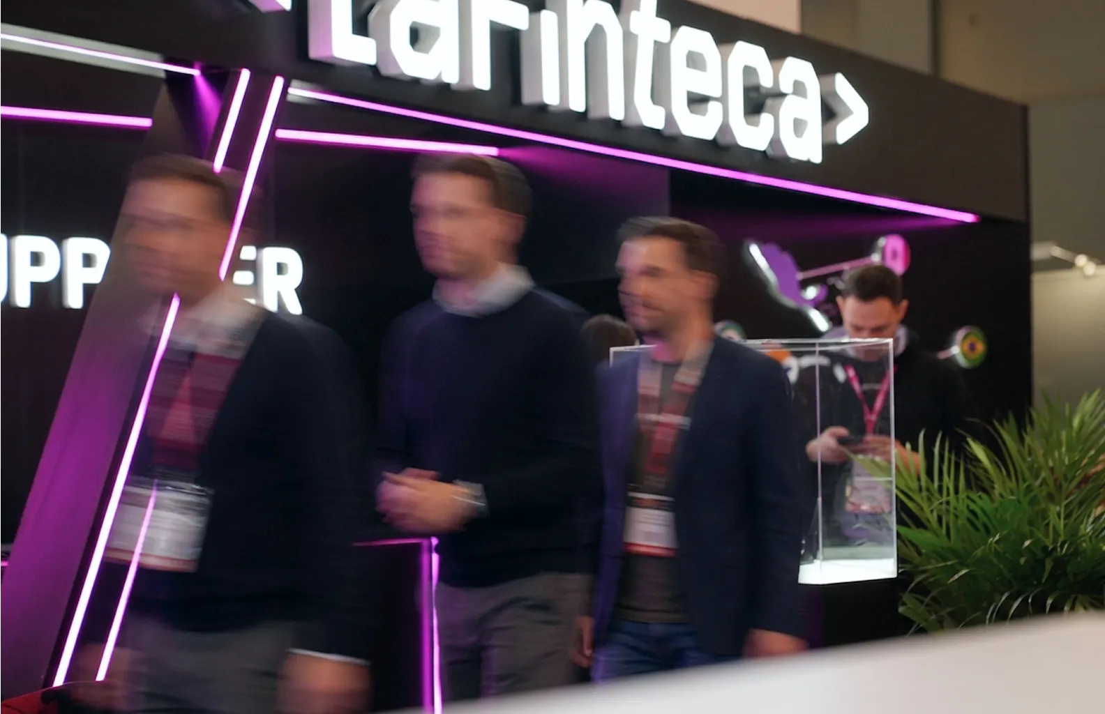 Attendees walking past the LaFinteca stand's illuminated signage at an industry trade show