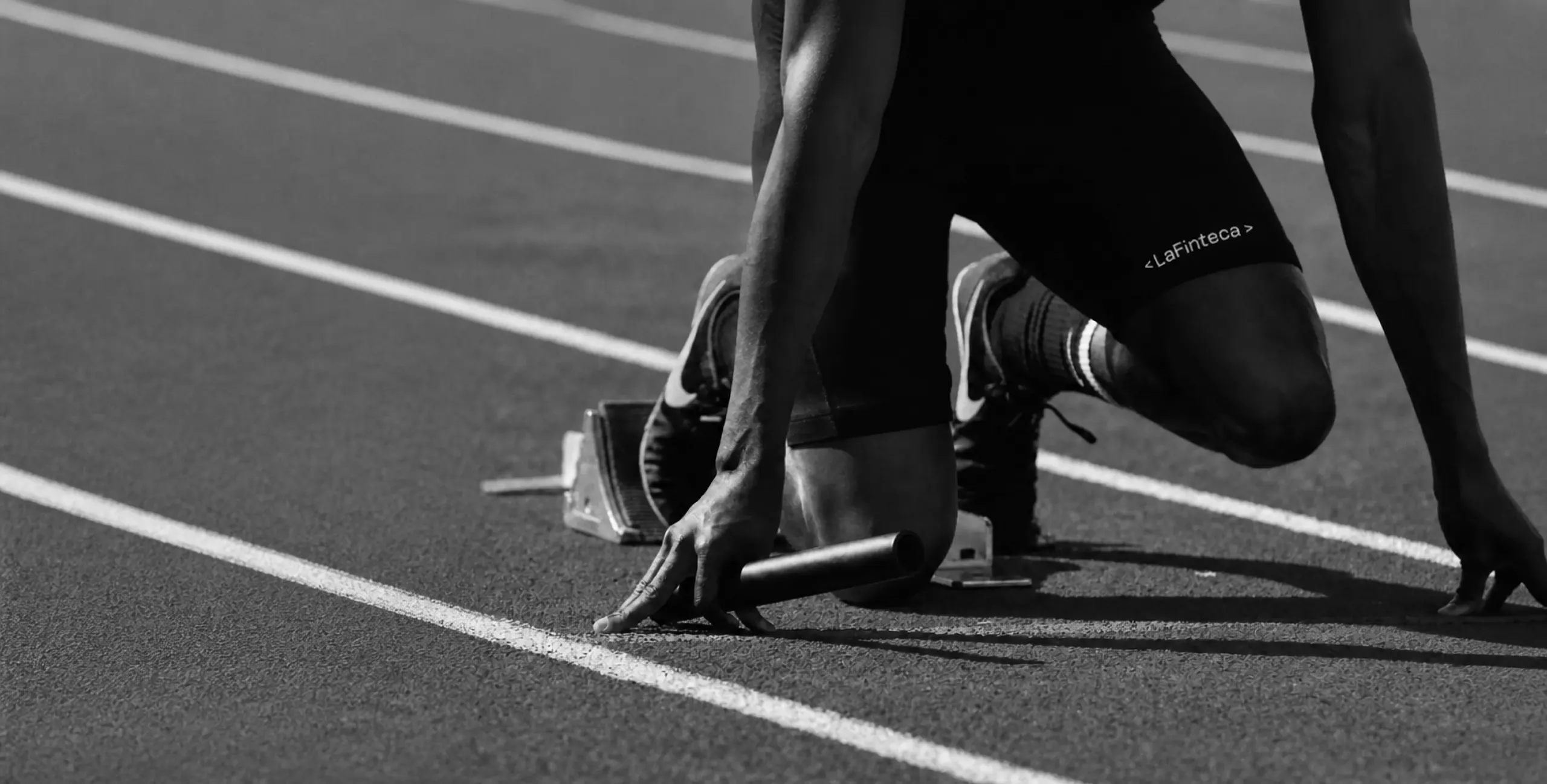 A relay runner in the starting blocks, black and white